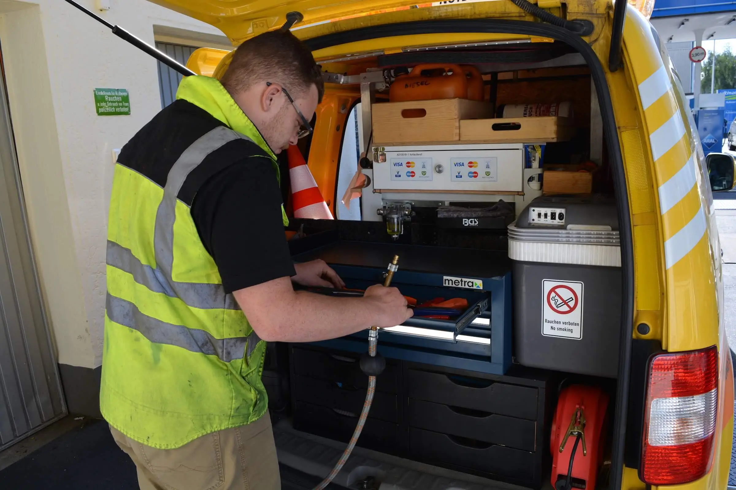 Techniker bedient die Pumpanlage im Heck des gelben Einsatzfahrzeugs